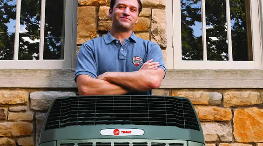 Trane Dealer Standing Behind Heat Pump With Arms Crossed (1)